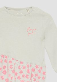 Lichtgrijze jurk met lange mouwen en een roze bloemenpatroon op de rok, met borduursel "bloemenmeisje" op de borst. Zachte katoenstof.