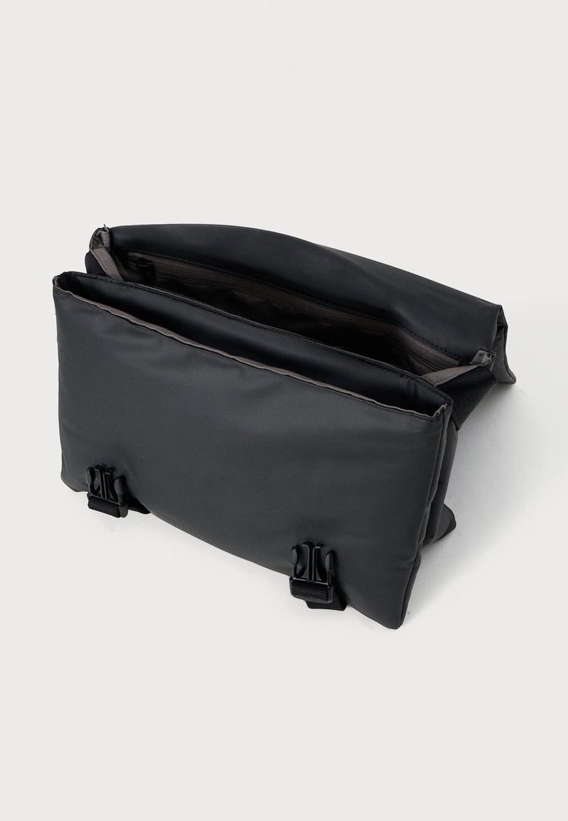 Svart rektangulär väska med en slät, matt yta. Har två fack och spännen för stängning. Inuti fodrad med tyg.