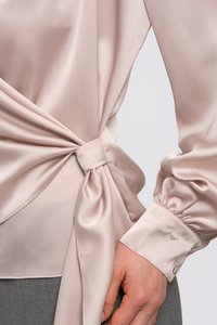 Helles rosa Satinhemd mit einem gebundenen Knoten-Detail an der Taille. Verfügt über lange, puffige Ärmel und einen geknöpften Bund. Glatte Textur.