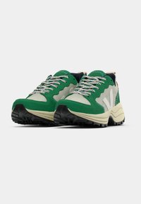 Rohelised seemisnahast ja halli tekstiilist tossud paksu valge tallaga, millel on mustriga paelad ja tekstureeritud musta kummist väljatallaga.