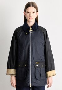 Tengerészkék vízálló dzseki kordb�ársony gallérral, arany színű fém kiegészítőkkel, két első zsebbel és kockás díszítéssel az ujjvégeken. Cipzáras elülső záródás.