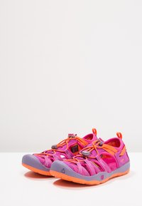 Sport sandaler med rosa og lilla tekstiloverdel, oransje detaljer, elastiske snører og gummierte såler. Lettvekts, åpen tå-design.