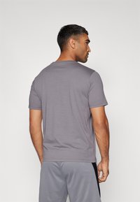 Camiseta gris de cuello redondo con mangas cortas, hecha de una suave mezcla de algodón. Costura trasera notable y diseño minimalista.