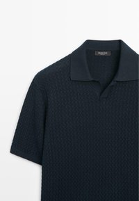 Polo en maille bleu marine à manches courtes avec motif texturé et col ouvert, étiqueté Massimo Dutti.