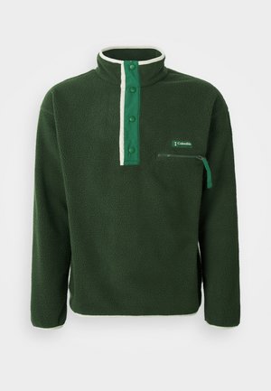 Green fleece pullover with a high collar, featuring a contrasting white zip, snap buttons, and a zippered chest pocket. Textured fabric.