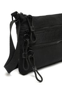 Czarna torebka crossbody z tkaniny z trzema zamykanymi na zamek komorami, płaskim designem, regulowanym paskiem i pętlami do łatwego chwytania.