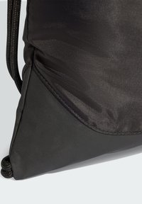 Čierna taška so sťahovacou šnúrkou s textúrovaným horným panelom a hladkým dolným panelom, so spevnenými švami a zaobleným tvarom.