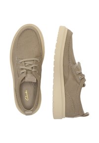 Beige kanvas snørebåndssko med syede detaljer og en let beige sål. Rund tå og lavtop-designet er velegnet til afslappet brug.