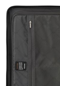 Interior de una maleta de viaje negra con un bolsillo de malla, compartimentos con cremallera y una etiqueta de tela que detalla la marca y las instrucciones de cuidado. Textura suave.