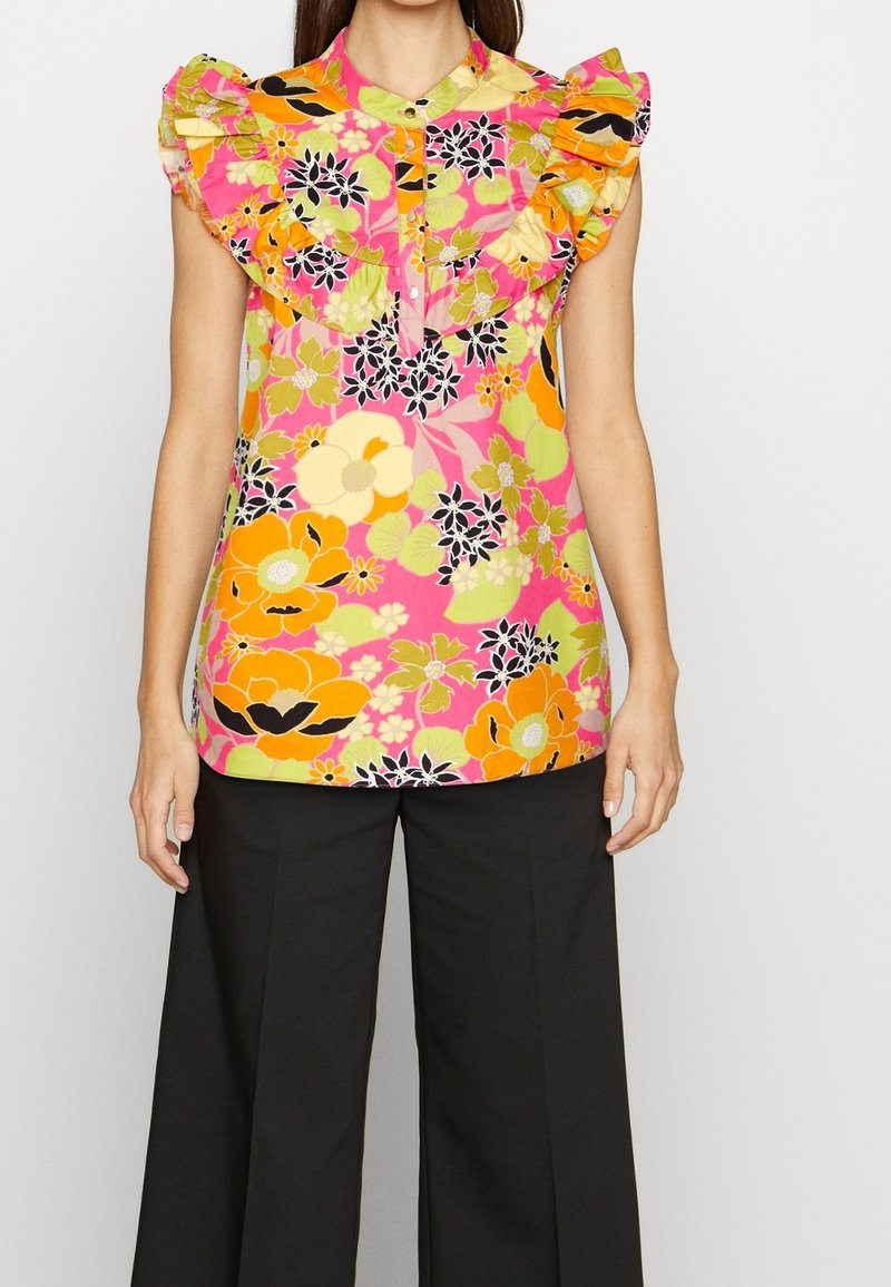 Colorful floral blouse with pink base, ruffled neckline, and short sleeves. Features large orange and yellow flowers complemented by black accents.