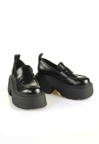 Melni platformas loafers ar spīdīgu lakotu apdari, plašu gumijas zoli un dekoratīvu siksniņu pāri vampam. Apaļa purngala dizains.