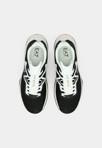 Fekete-fehér EA7 márkájú sportcipőpár fehér fűzőkkel, felülről nézve, egyszerű fehér háttéren.