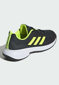 Czarne buty sportowe z neonowymi żółtymi akcentami, siateczkowa cholewka, lekka konstrukcja i biała gumowa podeszwa. Posiadają trzy paski i logo.
