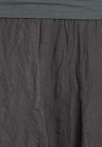 Grau Leinenrock mit einem gerafften Taillenbund, der eine strukturierte Oberfläche und natürliche Falten aufweist, was ihm ein fließendes Aussehen verleiht.