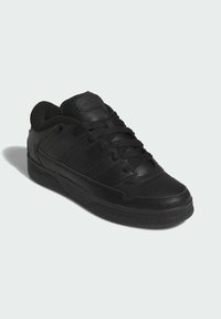 Scarpa sportiva nera con tomaia in pelle liscia e materiale sintetico, lacci neri spessi, punta perforata e suola in gomma resistente.