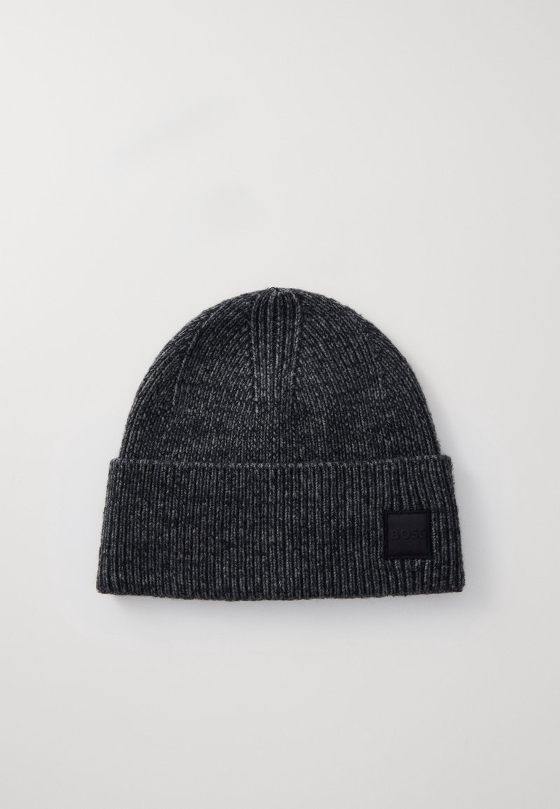 Bonnet en maille côtelée gris foncé avec revers plié et petite étiquette noire rectangulaire sur le revers, sur fond uni.