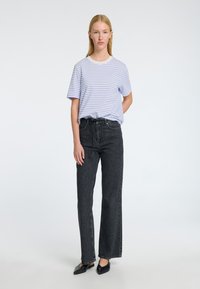 Ljuslila och vit randig kortärmad t-shirt i kombination med högmidjade svarta denimjeans med rak bendesign och en subtil textur.