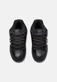 Baskets noires avec un dessus en cuir texturé, des accents perforés et des lacets plats. Le design comprend un col rembourré et un logo sur la languette.