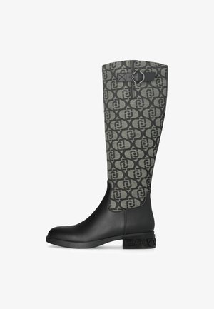 Stivale in pelle nera alto fino al ginocchio con asta in tessuto decorato, una fibbia decorativa vicino alla parte superiore e un tacco basso texturizzato.