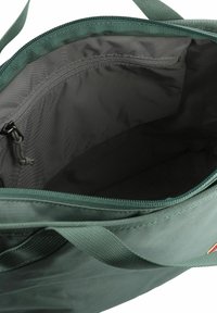 Groene stoffen totebag met een rits, met een grijze binnenkant en een binnenzak, versterkte hengsels en een soepele textuur.