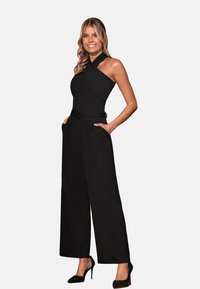 Černý overal s výstřihem na za krk, nařaseným pasem, širokými nohavicemi a kapsami. Vyrobeno z hladké látky s elegantním, těsně padnoucím střihem.