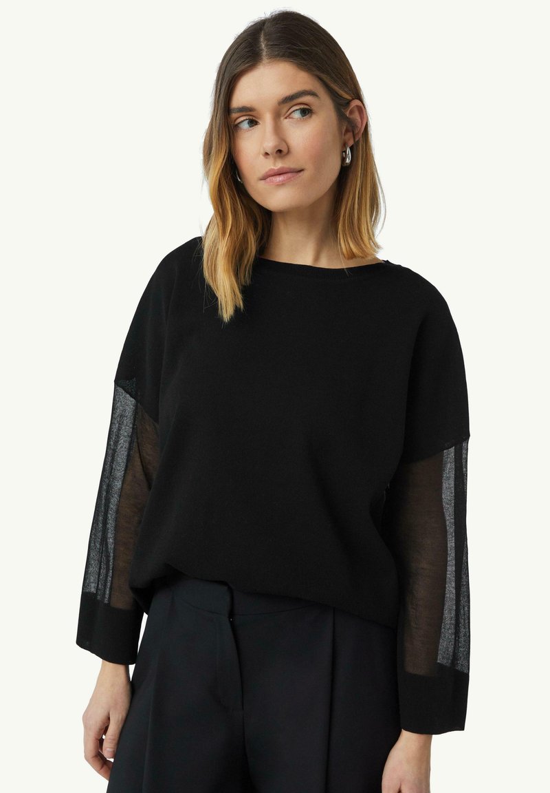 Schwarzer Pullover mit transparenten schwarzen Mesh-Ärmeln, rundem Ausschnitt und lockerer Passform. Weicher Textur mit kontrastierenden Materialien.