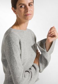 Grauer Wollpullover mit gerippter Textur, taillierter Passform und ausladenden Ärmeln. Verfügt über einen runden Ausschnitt und eine glatte, leicht flauschige Oberfläche.