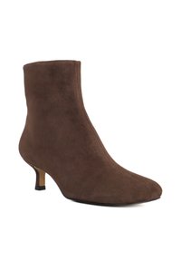 Bottine en suède marron avec un orteil pointu et un talon kitten fin. Texture lisse avec un design sans couture, sans fermetures visibles.