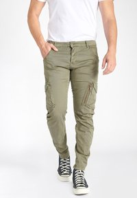 Olijfgroene cargobroek met een slim fit, voorzien van meerdere zakken en ritsen, gemaakt van lichtgewicht stof. Draag het met zwarte high-top sneakers.