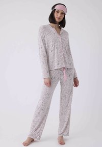 Kvinnors pyjamasset i ljusrosa med svarta djurmönster; har knäppt topp och byxor med dragsko och sidofickor; mjukt tyg.