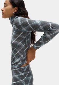 Maglioncino a maniche lunghe con collo alto in un morbido tessuto grigio testurizzato, con un motivo scozzese bianco e dettagli con spacco laterale per un tocco di stile in più.