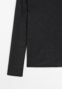 Langærmet top i mørkegråt strikkestof; har en glat tekstur og et enkelt, lige snit uden pynt.