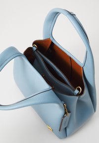 Light blue leather tote bag with textured finish, gold hardware, and brown interior. Features two handles and a detachable tag.