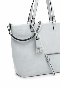 Sac fourre-tout gris clair avec doubles bretelles, poche zippée frontale avec tirette anneau et détail décoratif en pompon.