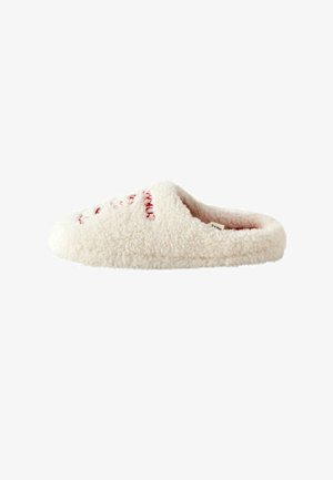 Cream-colored slipper made of fluffy material, featuring a rounded toe and red stitching details on the upper. Soft texture throughout.