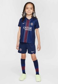 Marinblå Paris Saint-Germain fotbollsställ med diamantmönster, röda och blå detaljer samt en vit logotyp. Inkluderar shorts och strumpor.
