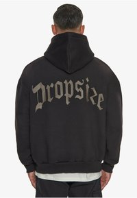 Schwarzer Kapuzenpullover mit einem auffälligen grauen "Dropsize"-Druck auf der Rückseite. Hergestellt aus weichem Material mit gerippten Bündchen und Saum.