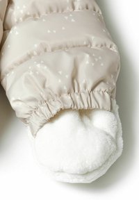 Moufles rembourrées beige avec des motifs triangulaires en blanc, doublure en douce polaire blanche au niveau du poignet, et poignet élastiqué pour un ajustement serré.