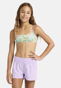 Maillot de bain avec un haut à motifs composés de carrés verts, roses et bleus, assorti à un short uni lavande portant l'inscription "ROXY" en blanc.