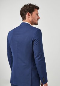 Marineblaues maßgeschneidertes Sakko mit Revers, einem Ein-Knopf-Verschluss und langen Ärmeln, die jeweils vier schwarze Knöpfe an den Manschetten haben.