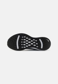 Rubber athletic shoe sole in black and white, featuring a textured surface with circular and rectangular patterns for traction.