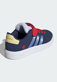 Marineblauwe sneaker met rode veters en band, lichtblauwe zijkanten, witte zool, gele hieltab met rode tekst en klein rood appellogo.
