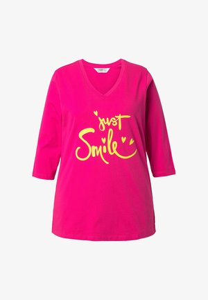 Helles pinkes Baumwoll-T-Shirt mit V-Ausschnitt und dreiviertel Ärmeln. Verziert mit gelbem Text "just Smile" und dekorativen Herzakzenten.