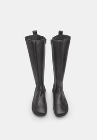 Mustad must reisikindad, millel on sile viimistlus, ümar varvas ja taga lukuga. Pehme sisemus ja kontrastse tekstuuriga kangas ülaosa juures.