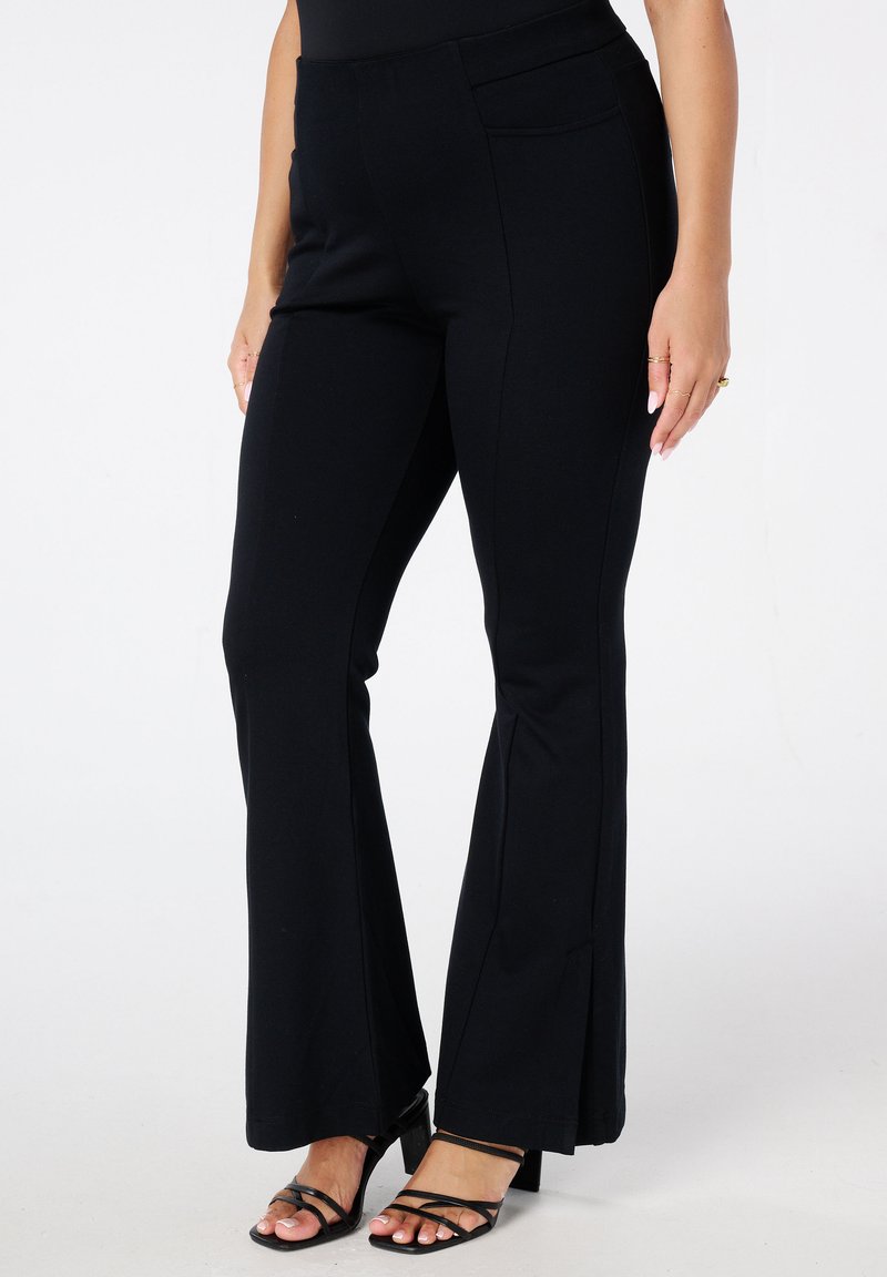 Zwarte flared broek van rekbare stof met een gladde textuur, met een strakke taille en een enkele zak op de achterkant.