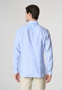 Camicia button-up a righe blu chiaro e bianche, con maniche lunghe e colletto. Il tessuto appare strutturato con polsini standard.