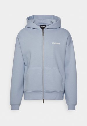Sweat à capuche zippé bleu clair avec poches devant, logo WRSTBHVR sur la poitrine et capuche avec cordon.