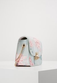 Helleblauen Handtasche mit floralen Mustern, goldener Kettenriemen, weichem Ledertextur und einem quadratischen goldenen Verschluss auf der Vorderseite.