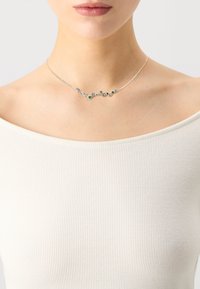 Silver chain necklace featuring multiple round gemstones in blue, green, and clear hues, arranged in a delicate, curved design.