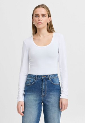 Weißer Langarm-Body mit einem Rundhalsausschnitt, kombiniert mit hochtaillierten blauen Jeans im abgewetzten Design und klassischem Fünf-Taschen-Stil.